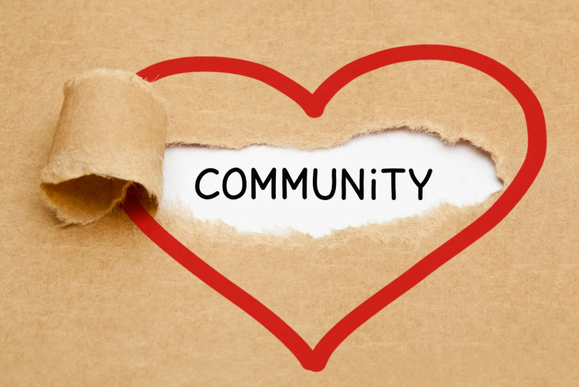 Image of a red heart outline on brown paper with the word ‘COMMUNITY’ revealed underneath torn section